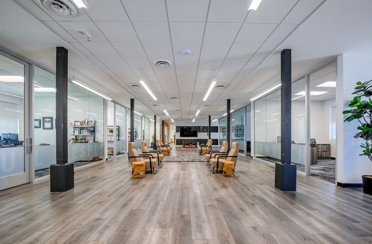 The main corridor: glass-fronted suites, timber accents and lounge seating in daylight