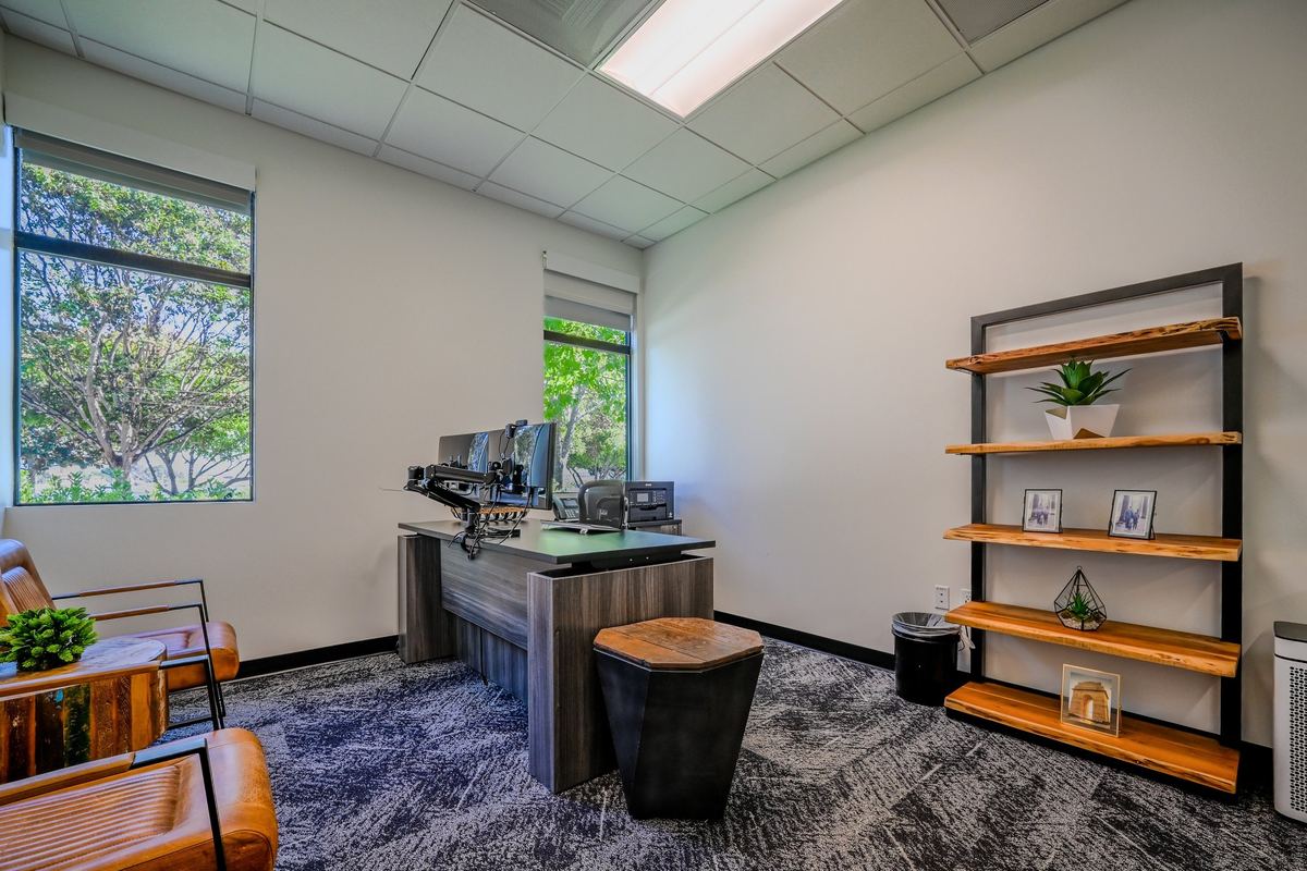 Suite 108: executive desk, timber shelving and leather chairs with windows on two walls